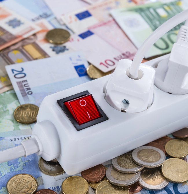 stos monet i banknotów euro na których leży przedłużacz